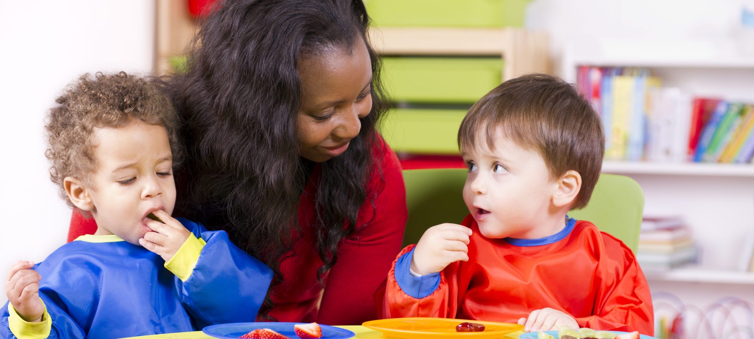 Woman sitting with two young boys who are eating fruit