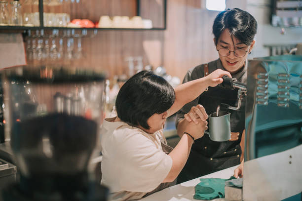 asian down syndrome female learning from barista making coffee in her café place of work